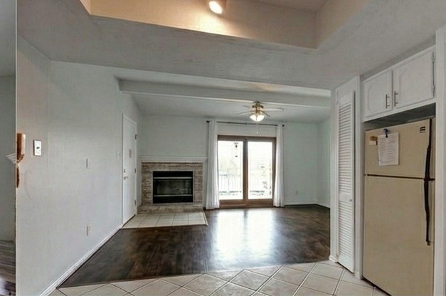 Living room looking toward fireplace, deck, and kitchen with white cabinets